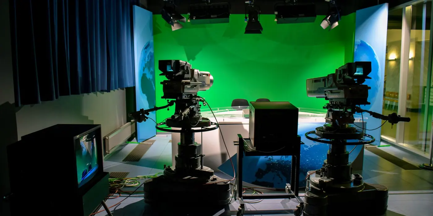 Studio televisivo con telecamere su piedistallo e fondale verde